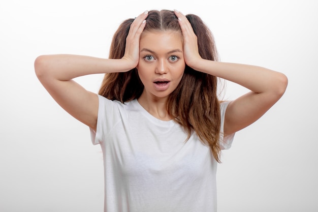 Shocked emotional excited woman with opened mouth is holding her head.