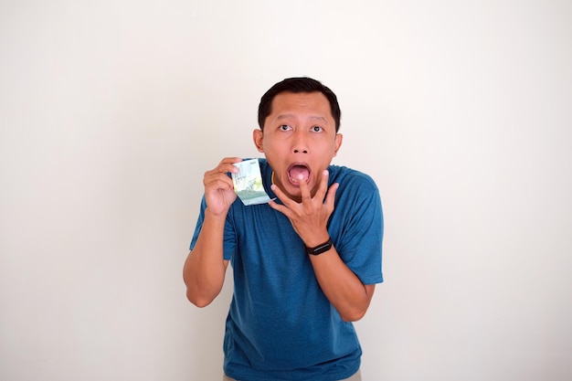 Shocked expression of Asian man while holding a money