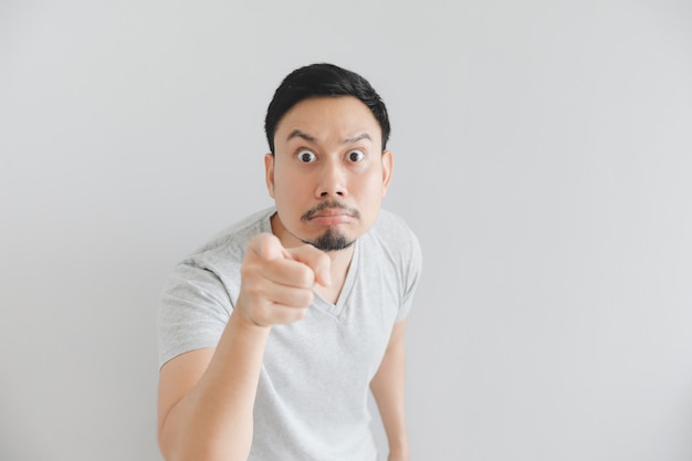 Shocked face of man in grey t-shirt with hand point on empty space.