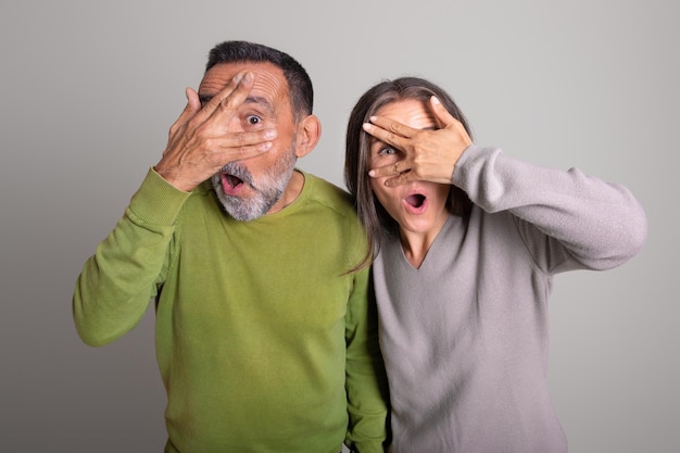 Shocked frightened old european man and woman with open mouth covers eyes with hands
