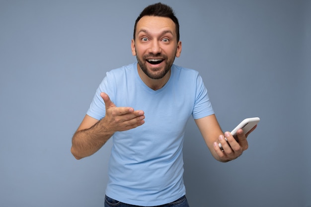 Shocked handsome young bearded brunet man wearing everyday blue t-shirt