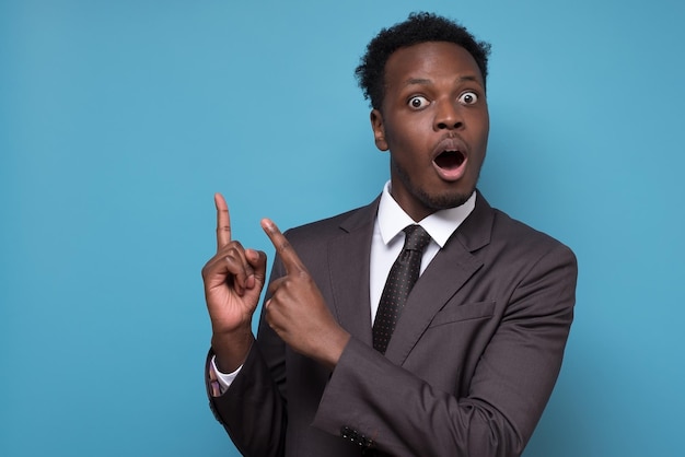 Shocked handsome young black business man pointing his hand up