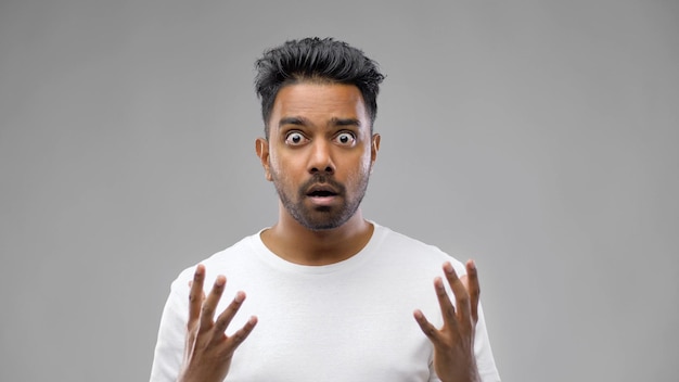 shocked indian man over grey background
