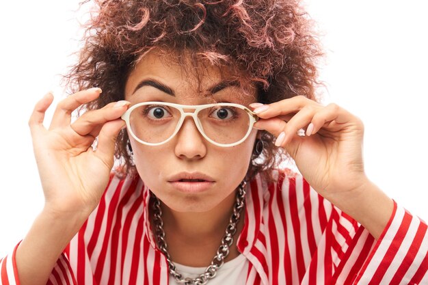 La faccia scioccata della ragazza kazaka con riccioli afro e occhiali sembra un primo piano sorpreso su sfondo bianco per studio con spazio per la copia