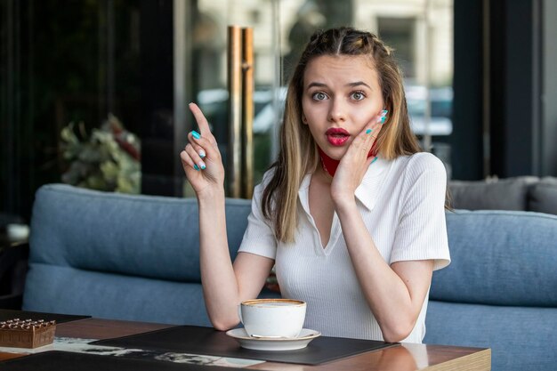 Shocked lady sitting at the restaurant and pointing her finger up