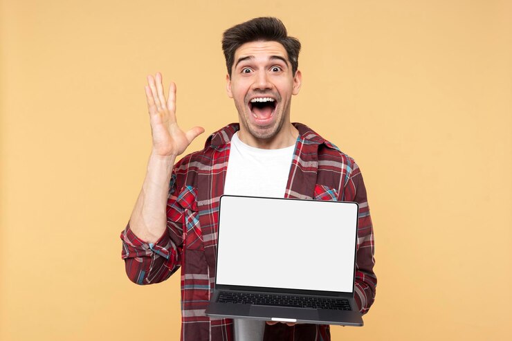 फोटो shocked man gesticulating and shouting demonstrating laptop with a blank screen looking at camera