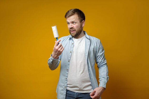 Shocked man looking at roll with duct tape which had just cleaned his clothes from animal hair