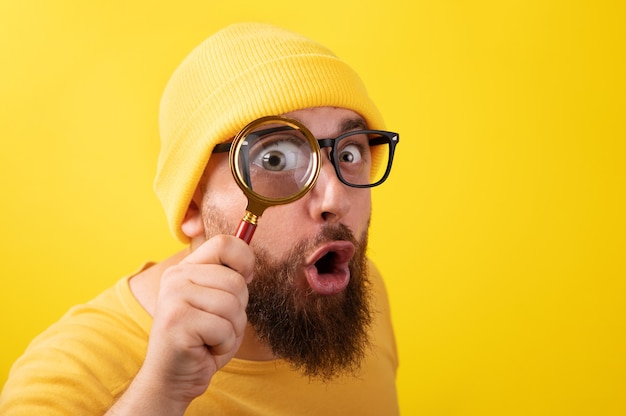 Photo shocked man with magnifier over yellow background
