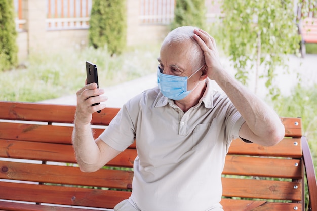 Shocked man with medical face mask using the phone to search for news