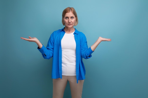 Shocked mature woman on blue background with copyspace