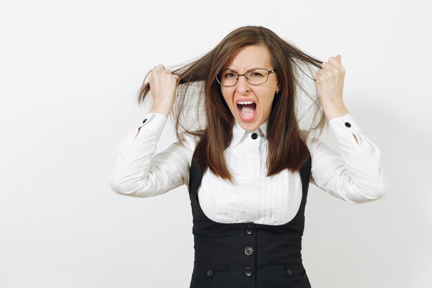 Shocked perplexed stress angry caucasian young business woman in black suit, white shirt and glasses tearing her hair isolated on white wall