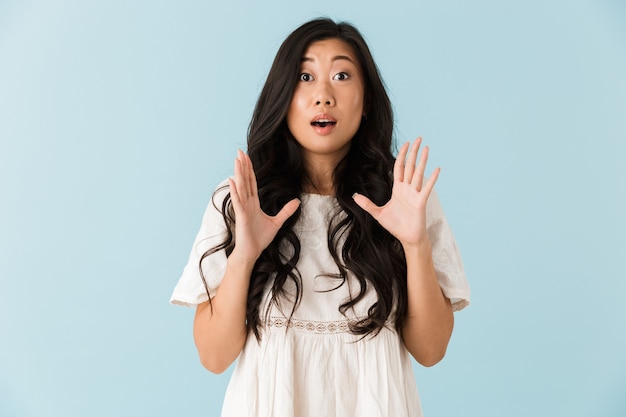 Shocked scared young asian beautiful woman posing isolated over blue wall