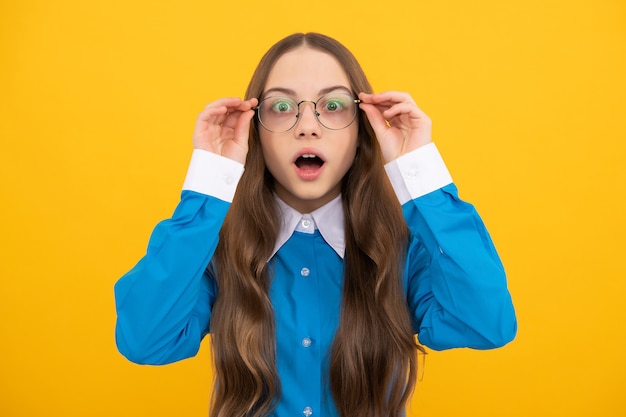 Shocked school aged girl child in spectacles with amazed look yellow background, amazement.