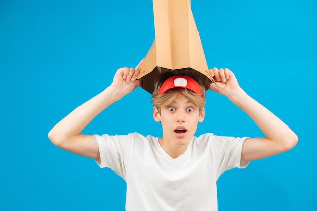 Shocked seller teen boy with paper bag over head Teenager holding paper bag over the head posing in studio