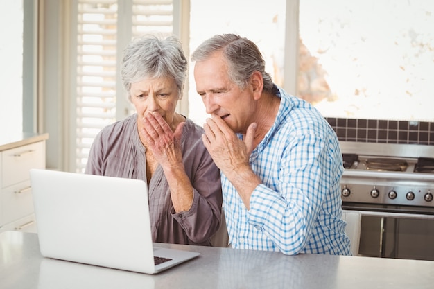 Shocked senior couple looking at laptop