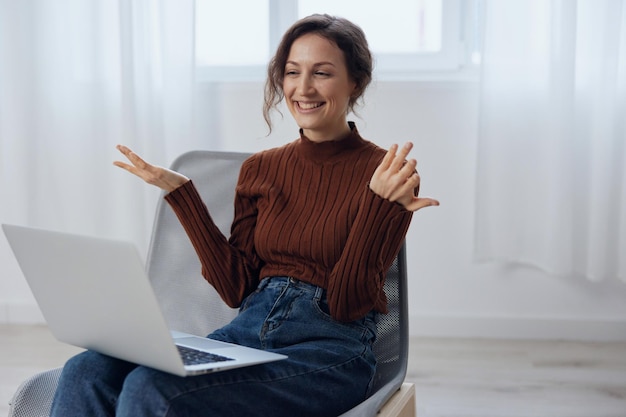 Shocked surprised happy curly awesome woman talks with friend\
in video conference call tells about latest cool news holds laptop\
raise hand active gesturing in chair distance communication\
concept