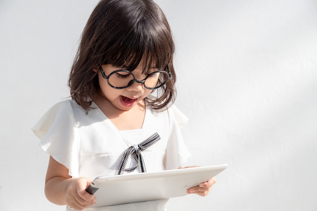 Шокированная и удивленная маленькая девочка в Интернете с концепцией цифрового планшетного компьютера для изумления
