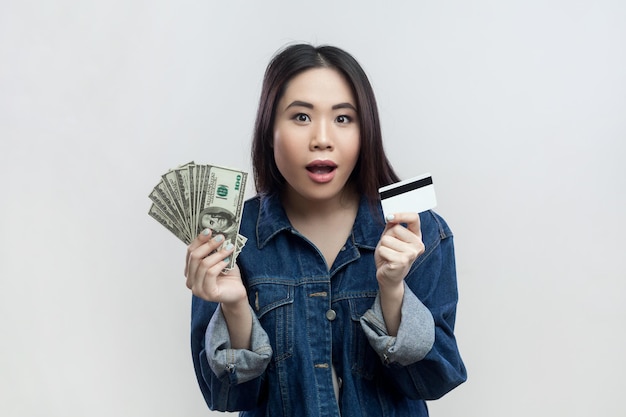 Shocked surprised woman looking at camera with open mouth holding dollar banknotes and credit card