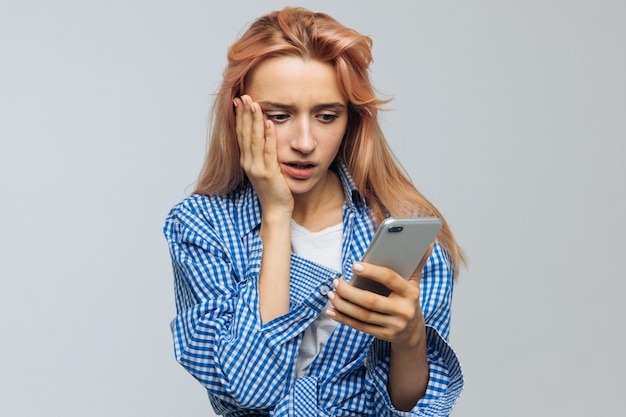 Photo shocked surprised woman looking at phone, receives sms, news, message, shocked