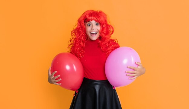 shocked teen child with party balloon on yellow background