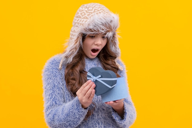 Shocked teen girl wear earflap hat with purchase ox on yellow background valentine