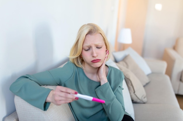 Donna scioccata che guarda la linea di controllo sul test di gravidanza singola donna triste che si lamenta in possesso di un test di gravidanza donna depressa con test di gravidanza negativo