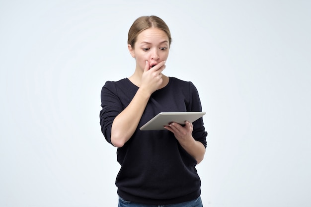 Shocked woman looking at digital tablet with surprise