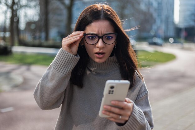 Photo shocked woman receiving a scam call holding her eyeglasses