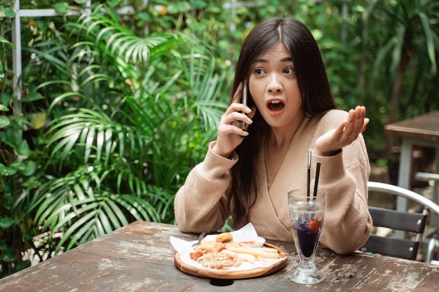 Shocked woman talking on phone