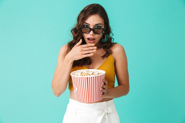 Vetri d'uso colpiti della donna che tengono secchio con popcorn e che esaminano macchina fotografica