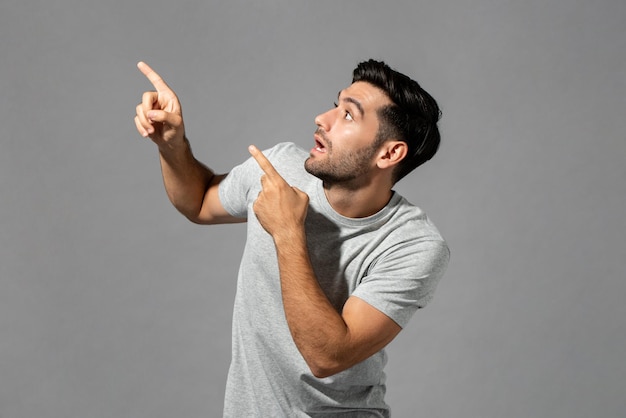 Foto scioccato giovane uomo caucasico ansimante con le mani rivolte verso l'alto isolato sfondo grigio chiaro dello studio