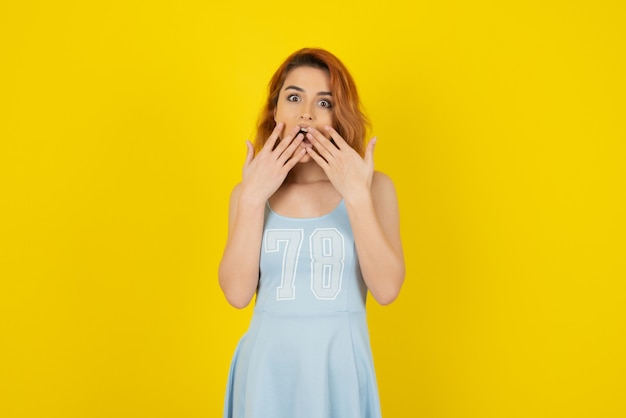 Shocked young girl on yellow wall