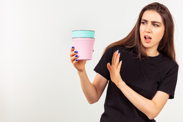 Shocked young lady holding colorful flower pots on looking at them