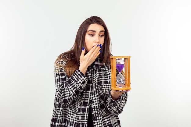 Shocked young lady holding hourglass and looking at it