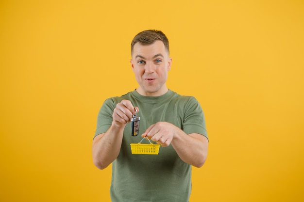 Shocked young man posing isolated on yellow orange background, studio portrait. People emotions lifestyle concept. Mock up copy space. Holding in hand car keys, showing thumb up