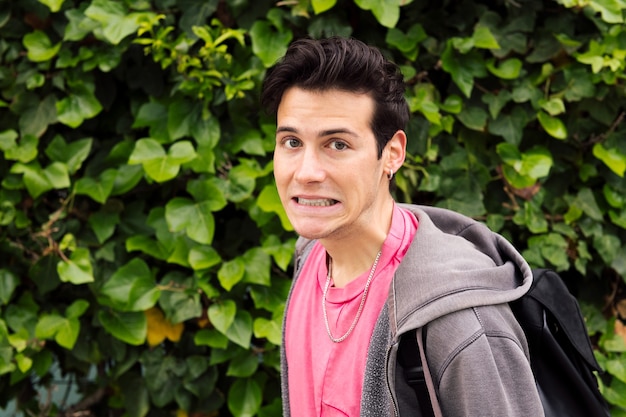 Shocked young man surprised on a green plants background concept of human expressions