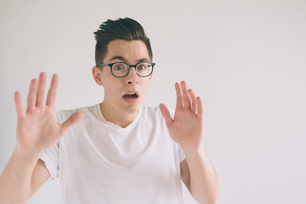 Shocked young man with glasses is looking at the camera