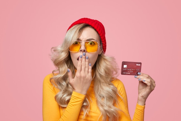 Фото Шокированная молодая женщина закрывает рот и демонстрирует кредитную карту в студии