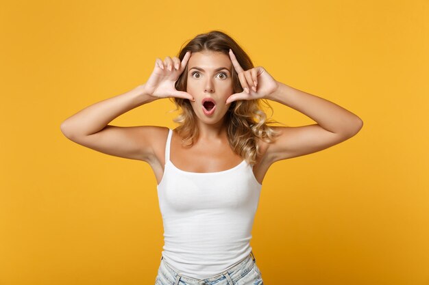 Shocked young woman girl in light casual clothes posing isolated on yellow orange wall background studio portrait. People lifestyle concept. Mock up copy space. Keeping mouth open, stretching eyelids.