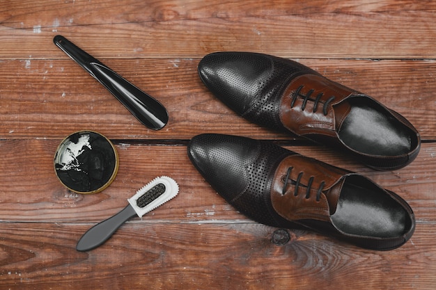 Shoe care. Shoe wax and brushes on wooden surface.