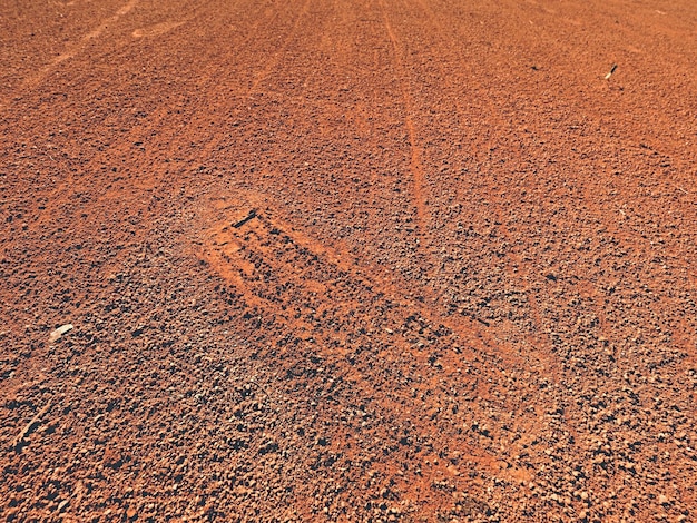 露天テニス場の乾燥した淡い赤い粉されたレンガの表面での靴の足跡