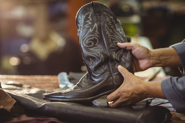 Photo shoemaker holding a leather boot