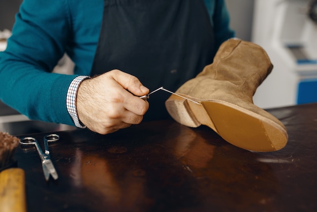 Photo shoemaker stitches the shoe, footwear repair service