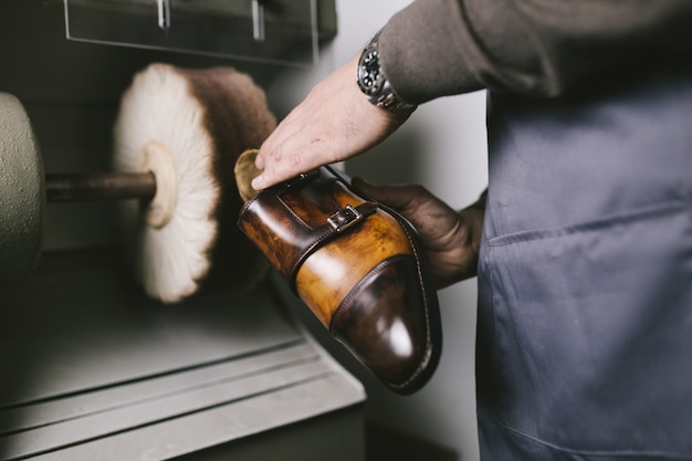 Shoemaker in workshop polishing new handmade beautiful leather shoes.