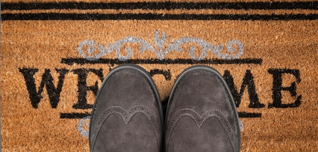 Photo shoes on new welcome doormat on wooden floor