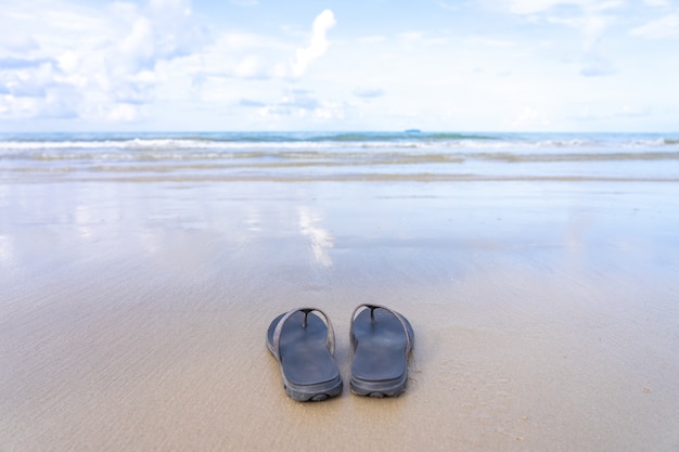 Shoes were placed on the beach by the sea, reflecting the sky. 