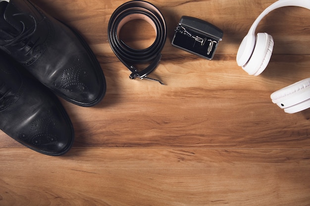 Shoes with belt and earphone on wooden