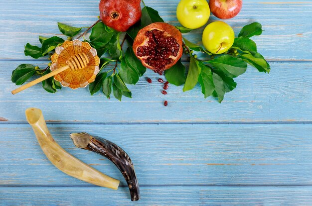 Shofar and honey with apple on blue wooden table.
