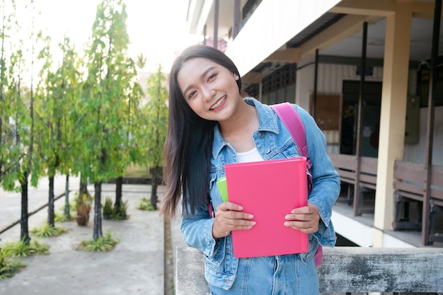 Photo shool girl hold book with backpak standing at campus