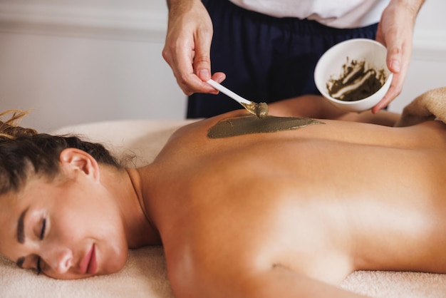 Shoot of a beautiful young woman enjoying during a seaweed mud treatment at the beauty salon.